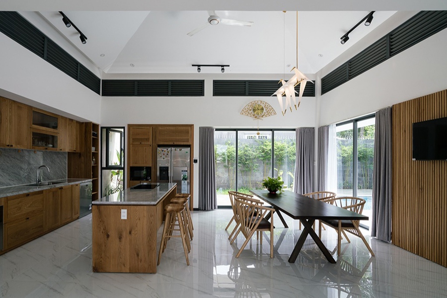 Không gian phòng bếp – ăn rộng thoáng với những ô cửa kính lớn mở ra sân vườn. Màu sắc chủ đạo của nội thất là màu trắng, kết hợp với màu gỗ tự nhiên.
