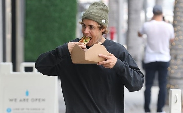 Justin Bieber thản nhiên ăn pizza khi đi dạo bộ trên phố ở Beverly Hills