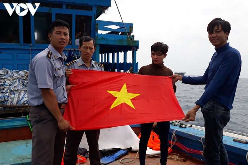 Cán bộ, kiểm ngư viên Chi đội Kiểm ngư 4 tặng cờ Tổ quốc cho ngư dân khai thác trên biển.