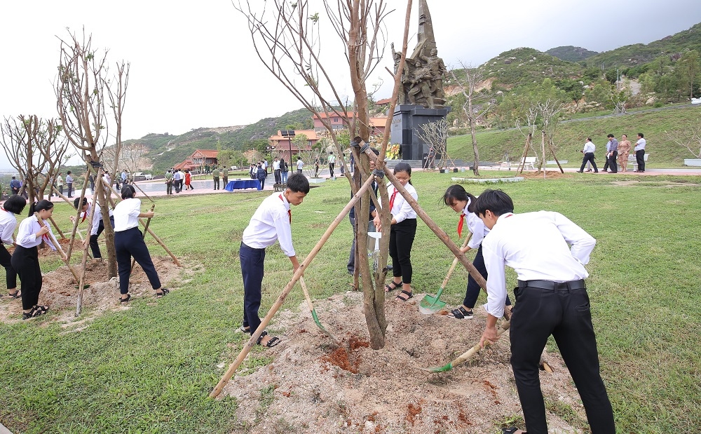 Các em học sinh trồng cây và chụp hình lưu niệm bên những cây xanh vừa trồng trong chương trình “Quỹ 1 triệu cây xanh cho Việt Nam”