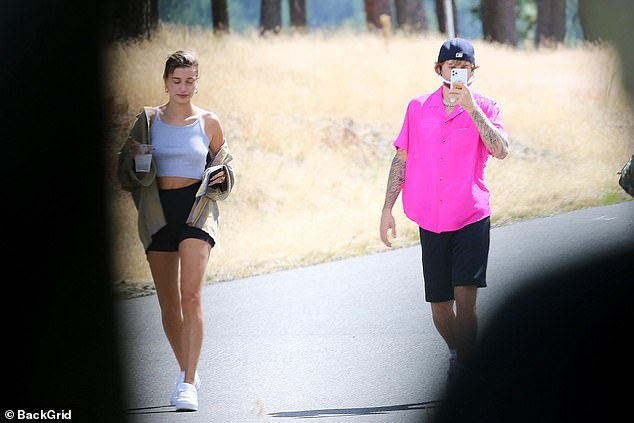 Justin Bieber mặc áo hồng rực, liên tục sử dụng điện thoại khi đi chơi cùng vợ