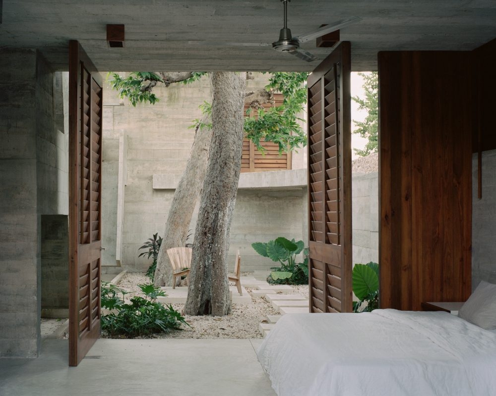 Phòng ngủ nhẹ nhàng với màu trắng, có cửa lớn đi ra vườn cây xanh.
