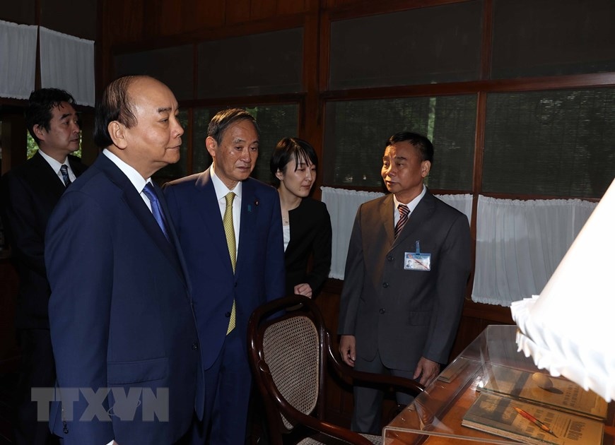Thủ tướng Nguyễn Xuân Phúc và Thủ tướng Nhật Bản Suga Yoshihide tham quan Nhà sàn Bác Hồ trong Khu Di tích Chủ tịch Hồ Chí Minh tại Phủ Chủ tịch. (Ảnh: Thống Nhất/TTXVN)