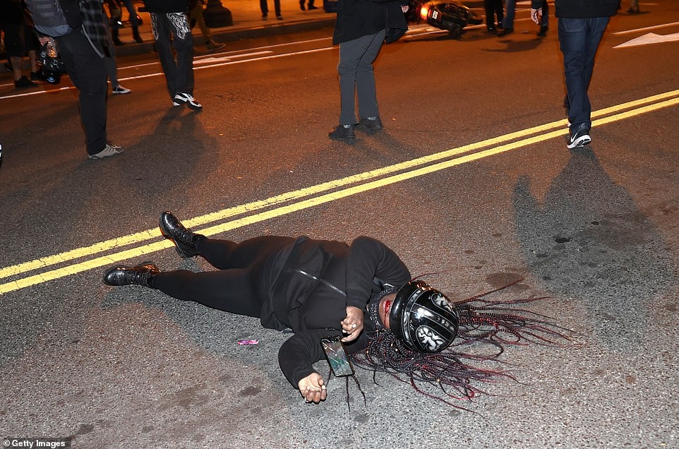 Một phụ nữ biểu tình da đen (thuộc phe ủng hộ Biden và phản đối Trump) bị thương, chảy máu miệng, và nằm bên vệ đường trong cuộc xô xát giữa 2 phe ở thủ đô Washington (Mỹ).
